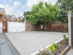 a driveway with a white gate and a brick wall at The Stables in Worcester