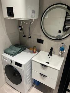 a small bathroom with a washing machine and a sink at White and Black Apartments in Katowice