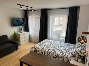 a bedroom with a bed and a couch and two windows at White and Black Apartments in Katowice