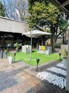 un patio con mobili bianchi e ombrellone di Pari Guest House a Middelburg