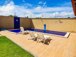 a swimming pool with three chairs and a pool at Nos Lençóis Dunas Residence 9 in Santo Amaro