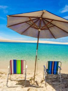 two chairs and an umbrella on a beach at Nos Lençóis Dunas Residence 9 in Santo Amaro