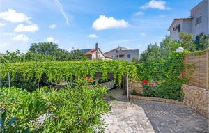 einen Garten mit einer Hecke und Blumen sowie ein Gebäude in der Unterkunft Amazing Apartment In Murter With Wifi in Murter