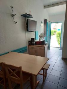 uma cozinha com uma mesa e cadeiras e uma televisão em Maisonnette eau turquoise em Argelès-sur-Mer