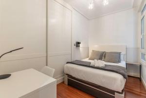 a small white bedroom with a bed and a desk at Apartamento La Alameda de Indautxu in Bilbao