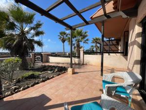 a patio with chairs and palm trees on a house at Adam Home Origo Mare in Lajares