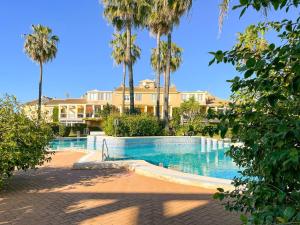 a swimming pool in front of a house with palm trees at Apartamento les Marines in Denia