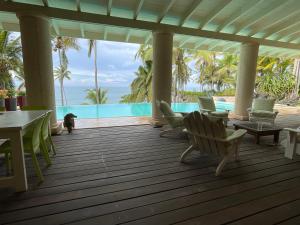 a porch with chairs and a dog looking out at the ocean at Guestroom los gorgones in Las Galeras