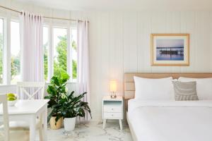 a white bedroom with a bed and a desk and windows at The Sunset Montauk in Montauk