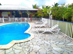a swimming pool with two lounge chairs next to a fence at Gites VASSEAUX in Capesterre-Belle-Eau