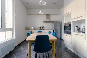 cocina con mesa de madera y sillas azules en Coeur de ville #H3 - WIFI et NETFLIX - Lave linge - Logement partagé - Chambre privée en Cholet