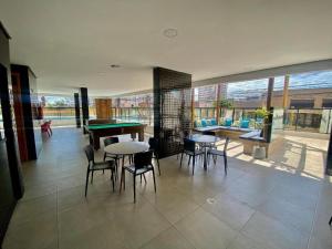 a living room with tables and chairs and a pool table at Apto Corais do Mar 290m Praia Jatiuca in Maceió