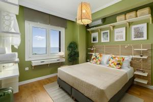 um quarto com paredes verdes e uma cama com uma janela em Azure Breeze - Coastal Chic Getaway by the Sea em Psakoudia