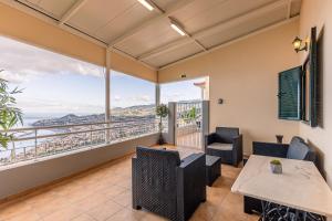 a living room with a table and chairs and a balcony at Villa das Furnas in Funchal