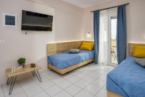 1 dormitorio con 2 camas, TV y mesa en Sofia's Apts en Hersonissos