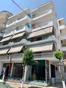 un bâtiment blanc avec des arbres devant lui dans l'établissement Hotel Piazza, à Saranda