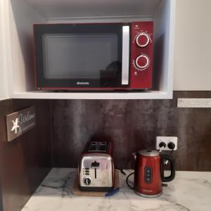 a microwave on a shelf with a coffee maker and a toaster at Papamoa Beach Hugoway, Pohutukawa Studio Deluxe, Close beach, free parking in Papamoa