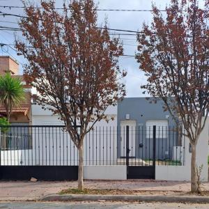 dos árboles frente a un edificio con una valla en Departamento Temporario La Plaza en Córdoba