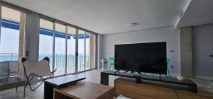 sala de estar con TV de pantalla plana grande en A pie de playa, en Torrevieja