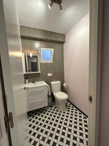 a bathroom with a white toilet and a black and white tiled floor at Imperium Apartamentos Centro Parking Gratis in Mérida +37 photos