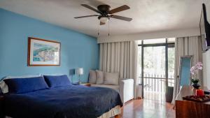 a blue bedroom with a bed and a ceiling fan at Toca Madera in Chapala
