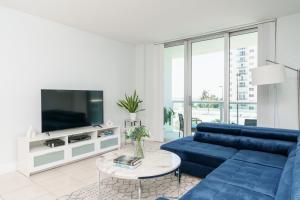 a living room with a blue couch and a tv at Modern 1 BDR Oceanview with direct beach access! in Hollywood