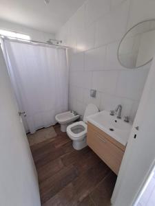 a white bathroom with a toilet and a sink at Departamento Temporario La Plaza in Córdoba