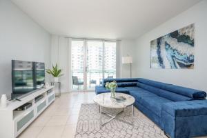 a living room with a blue couch and a tv at Modern 1 BDR Oceanview with direct beach access! in Hollywood