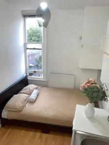 ein kleines Bett in einem Zimmer mit Fenster in der Unterkunft Great location studio apartment with Smart TV and workspace in London