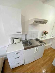una pequeña cocina blanca con fregadero y encimera en Great location studio apartment with Smart TV and workspace en Londres