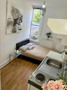 um pequeno quarto com uma cama e uma janela em Great location studio apartment with Smart TV and workspace em Londres