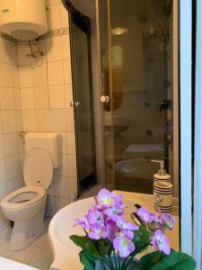a bathroom with a toilet and a sink with purple flowers at Tranquil verde in Matulji