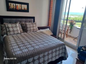 a bedroom with a bed and a balcony with a view at Reservas del peñon in Girardot