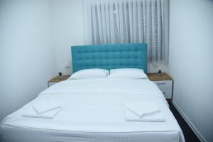 a bedroom with a bed with a blue headboard and a window at Vb apartmani in Prijedor