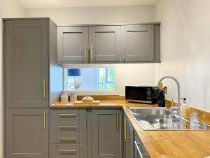 a kitchen with gray cabinets and a sink at The Yorkshire Hosts - The Tailor's Lounge in Ripon