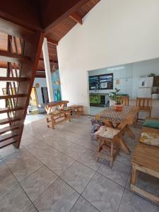 Habitación grande con mesas y bancos de madera. en Da Lua Hostel, en Ubatuba