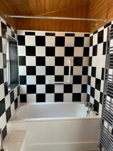 a bath tub in a bathroom with a checkered wall at Beautiful 4 bedroom house in Enfield in Enfield Lock