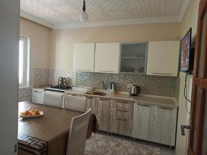 a kitchen with white cabinets and a table in it at Local Home in Çağlayan