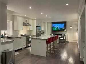una cocina con armarios blancos y un bar con taburetes rojos en Lux White Rock Pool House Beachfront Resort like, en Surrey