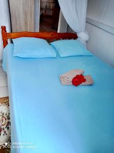 uma cama azul com uma flor vermelha em Chez Ninette près des sources chaudes em Bouillante
