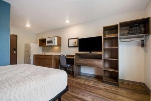 um quarto de hotel com uma cama e uma secretária com uma televisão em WoodSpring Suites Panama City Beach em Panama City Beach
