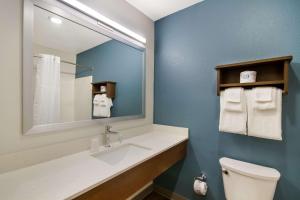La salle de bains est pourvue d'un lavabo, d'un miroir et de toilettes. dans l'établissement WoodSpring Suites Panama City Beach, à Panama City Beach