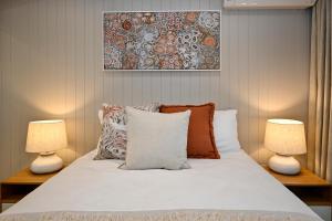 a bedroom with a white bed with two lamps at Stylish 2 b/r apartment - 4 guests, garage ZC5 in Alexandra Headland