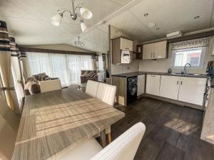 a kitchen and dining room with a table and chairs at Beautiful 8 Berth Caravan With Decking At Broadland Sands In Suffolk Ref 20017cv in Hopton on Sea
