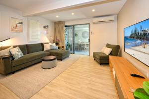 a living room with a couch and a flat screen tv at Stylish 2 b/r apartment - 4 guests, garage ZC5 in Alexandra Headland