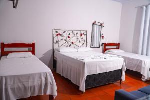 una camera con 2 letti con lenzuola bianche e specchio di Pousada Sol de Verão a Barra do Garças