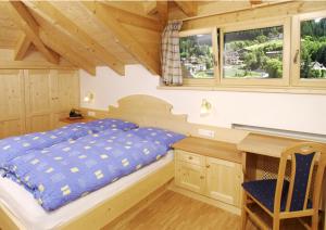 a bedroom with a bed and a desk and windows at Appartements Tlusel in Ortisei +55 photos
