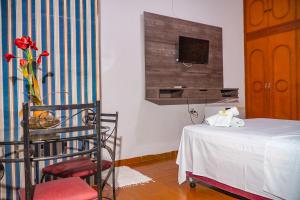 1 dormitorio con 1 cama, 1 silla y TV en Pousada Sol de Verão, en Barra do Garças