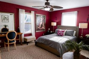 una camera da letto con pareti rosse, un letto e una scrivania di La Villetta a Dripping Springs