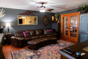 a living room with a leather couch and a ceiling fan at La Villetta in Dripping Springs